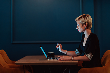 Image showing Businesswoman sitting in a cafe while focused on working on a laptop and participating in an online meetings. Selective focus.