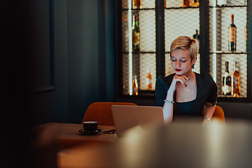 Image showing Businesswoman sitting in a cafe while focused on working on a laptop and participating in an online meetings. Selective focus.