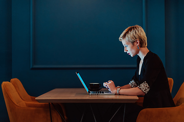 Image showing Businesswoman sitting in a cafe while focused on working on a laptop and participating in an online meetings. Selective focus.