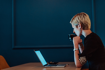 Image showing Businesswoman sitting in a cafe while focused on working on a laptop and participating in an online meetings. Selective focus.