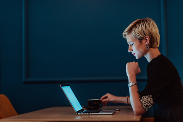 Image showing Businesswoman sitting in a cafe while focused on working on a laptop and participating in an online meetings. Selective focus.