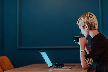 Image showing Businesswoman sitting in a cafe while focused on working on a laptop and participating in an online meetings. Selective focus.