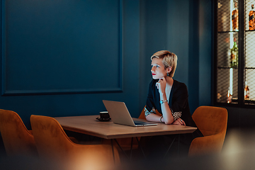 Image showing Businesswoman sitting in a cafe while focused on working on a laptop and participating in an online meetings. Selective focus.