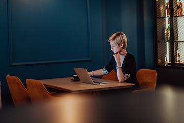 Image showing Businesswoman sitting in a cafe while focused on working on a laptop and participating in an online meetings. Selective focus.