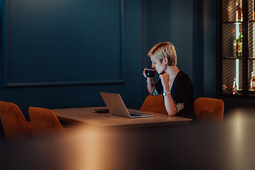 Image showing Businesswoman sitting in a cafe while focused on working on a laptop and participating in an online meetings. Selective focus.