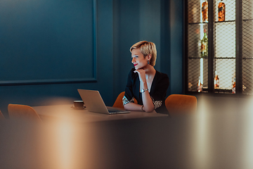 Image showing Businesswoman sitting in a cafe while focused on working on a laptop and participating in an online meetings. Selective focus.