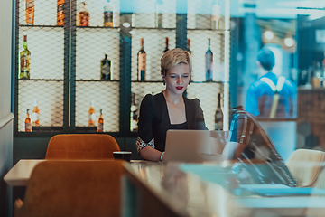 Image showing Businesswoman sitting in a cafe while focused on working on a laptop and participating in an online meetings. Selective focus.