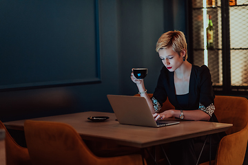 Image showing Businesswoman sitting in a cafe while focused on working on a laptop and participating in an online meetings. Selective focus.