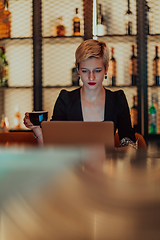 Image showing Businesswoman sitting in a cafe while focused on working on a laptop and participating in an online meetings. Selective focus.