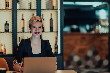 Image showing Businesswoman sitting in a cafe while focused on working on a laptop and participating in an online meetings. Selective focus.