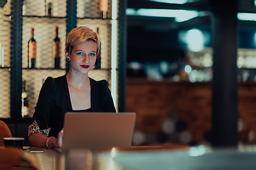 Image showing Businesswoman sitting in a cafe while focused on working on a laptop and participating in an online meetings. Selective focus.