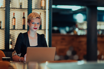 Image showing Businesswoman sitting in a cafe while focused on working on a laptop and participating in an online meetings. Selective focus.