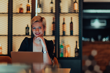 Image showing Businesswoman sitting in a cafe while focused on working on a laptop and participating in an online meetings. Selective focus.