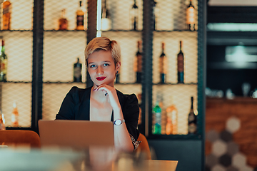 Image showing Businesswoman sitting in a cafe while focused on working on a laptop and participating in an online meetings. Selective focus.