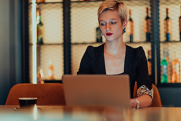 Image showing Businesswoman sitting in a cafe while focused on working on a laptop and participating in an online meetings. Selective focus.