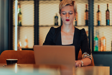 Image showing Businesswoman sitting in a cafe while focused on working on a laptop and participating in an online meetings. Selective focus.