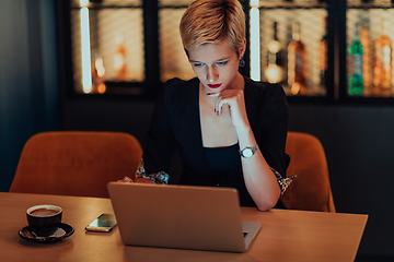 Image showing Businesswoman sitting in a cafe while focused on working on a laptop and participating in an online meetings. Selective focus.