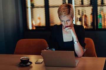 Image showing Businesswoman sitting in a cafe while focused on working on a laptop and participating in an online meetings. Selective focus.