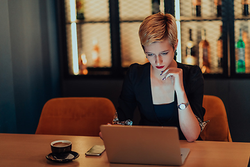 Image showing Businesswoman sitting in a cafe while focused on working on a laptop and participating in an online meetings. Selective focus.