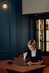 Image showing Businesswoman sitting in a cafe while focused on working on a laptop and participating in an online meetings. Selective focus.