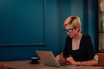 Image showing Businesswoman sitting in a cafe while focused on working on a laptop and participating in an online meetings. Selective focus.