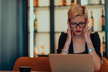 Image showing Businesswoman sitting in a cafe while focused on working on a laptop and participating in an online meetings. Selective focus.