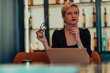 Image showing Businesswoman sitting in a cafe while focused on working on a laptop and participating in an online meetings. Selective focus.