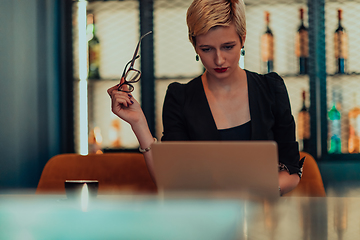 Image showing Businesswoman sitting in a cafe while focused on working on a laptop and participating in an online meetings. Selective focus.