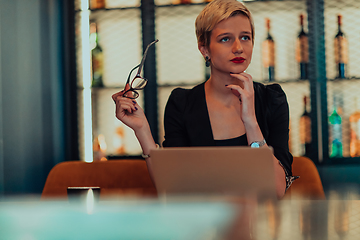 Image showing Businesswoman sitting in a cafe while focused on working on a laptop and participating in an online meetings. Selective focus.