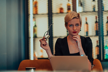 Image showing Businesswoman sitting in a cafe while focused on working on a laptop and participating in an online meetings. Selective focus.