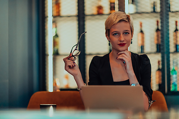 Image showing Businesswoman sitting in a cafe while focused on working on a laptop and participating in an online meetings. Selective focus.