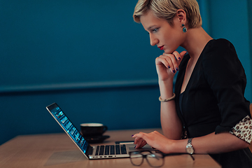 Image showing Businesswoman sitting in a cafe while focused on working on a laptop and participating in an online meetings. Selective focus.