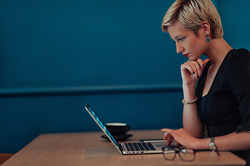 Image showing Businesswoman sitting in a cafe while focused on working on a laptop and participating in an online meetings. Selective focus.