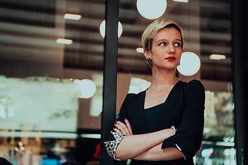 Image showing Business woman in a black suit, successful confidence with arms crossed in modern office