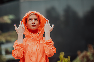 Image showing a woman in a sports outfit is resting in a city environment after a hard morning workout while using noiseless headphones