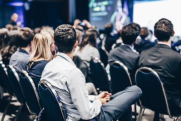 Image showing Speaker giving a talk in conference hall at business event. Rear view of unrecognizable people in audience at the conference hall. Business and entrepreneurship concept.