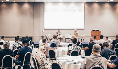 Image showing Speaker giving a talk in conference hall at business event. Rear view of unrecognizable people in audience at the conference hall. Business and entrepreneurship concept.