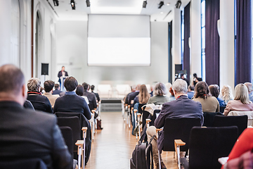 Image showing Speaker giving a talk in conference hall at business event. Rear view of unrecognizable people in audience at the conference hall. Business and entrepreneurship concept.