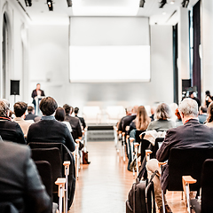 Image showing Speaker giving a talk in conference hall at business event. Rear view of unrecognizable people in audience at the conference hall. Business and entrepreneurship concept.