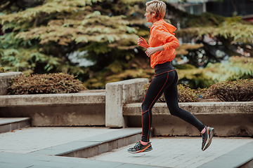 Image showing A blonde in a sports outfit is running around the city in an urban environment. The hot blonde maintains a healthy lifestyle.