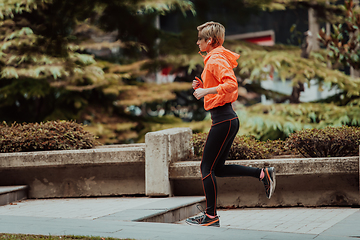 Image showing A blonde in a sports outfit is running around the city in an urban environment. The hot blonde maintains a healthy lifestyle.