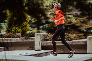 Image showing A blonde in a sports outfit is running around the city in an urban environment. The hot blonde maintains a healthy lifestyle.