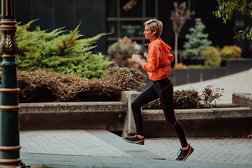 Image showing A blonde in a sports outfit is running around the city in an urban environment. The hot blonde maintains a healthy lifestyle.