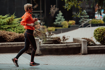 Image showing A blonde in a sports outfit is running around the city in an urban environment. The hot blonde maintains a healthy lifestyle.