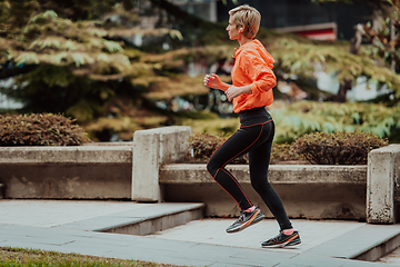 Image showing A blonde in a sports outfit is running around the city in an urban environment. The hot blonde maintains a healthy lifestyle.