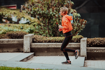 Image showing A blonde in a sports outfit is running around the city in an urban environment. The hot blonde maintains a healthy lifestyle.