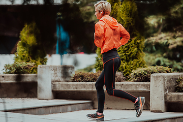 Image showing A blonde in a sports outfit is running around the city in an urban environment. The hot blonde maintains a healthy lifestyle.