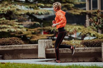 Image showing A blonde in a sports outfit is running around the city in an urban environment. The hot blonde maintains a healthy lifestyle.