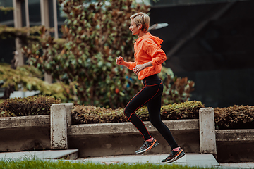 Image showing A blonde in a sports outfit is running around the city in an urban environment. The hot blonde maintains a healthy lifestyle.