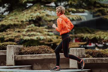 Image showing A blonde in a sports outfit is running around the city in an urban environment. The hot blonde maintains a healthy lifestyle.